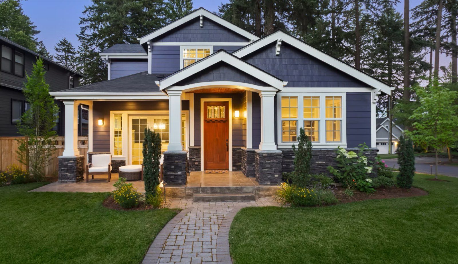 Craftsman-style custom home at dusk with lit windows and landscaped path
