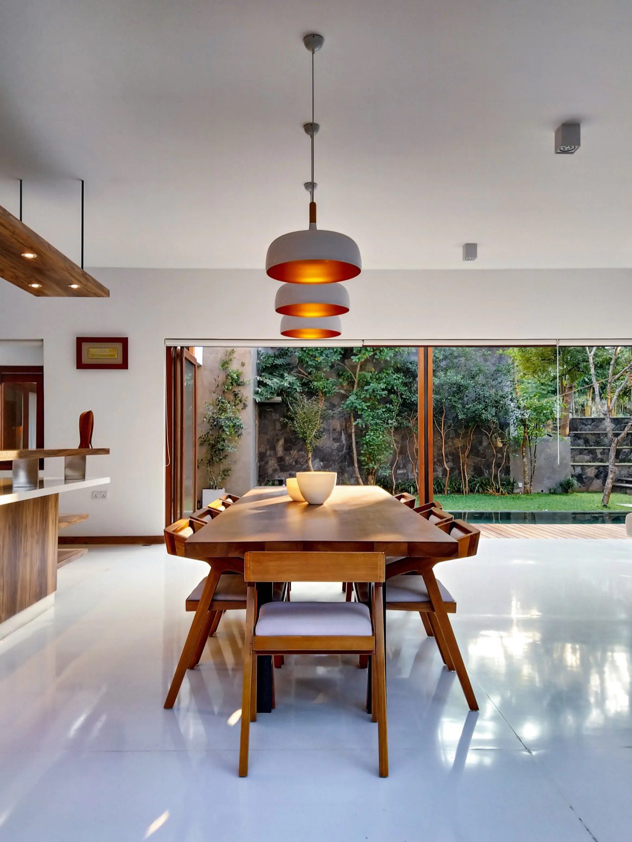 Dining area with timber table opening onto a garden through full-height glazing